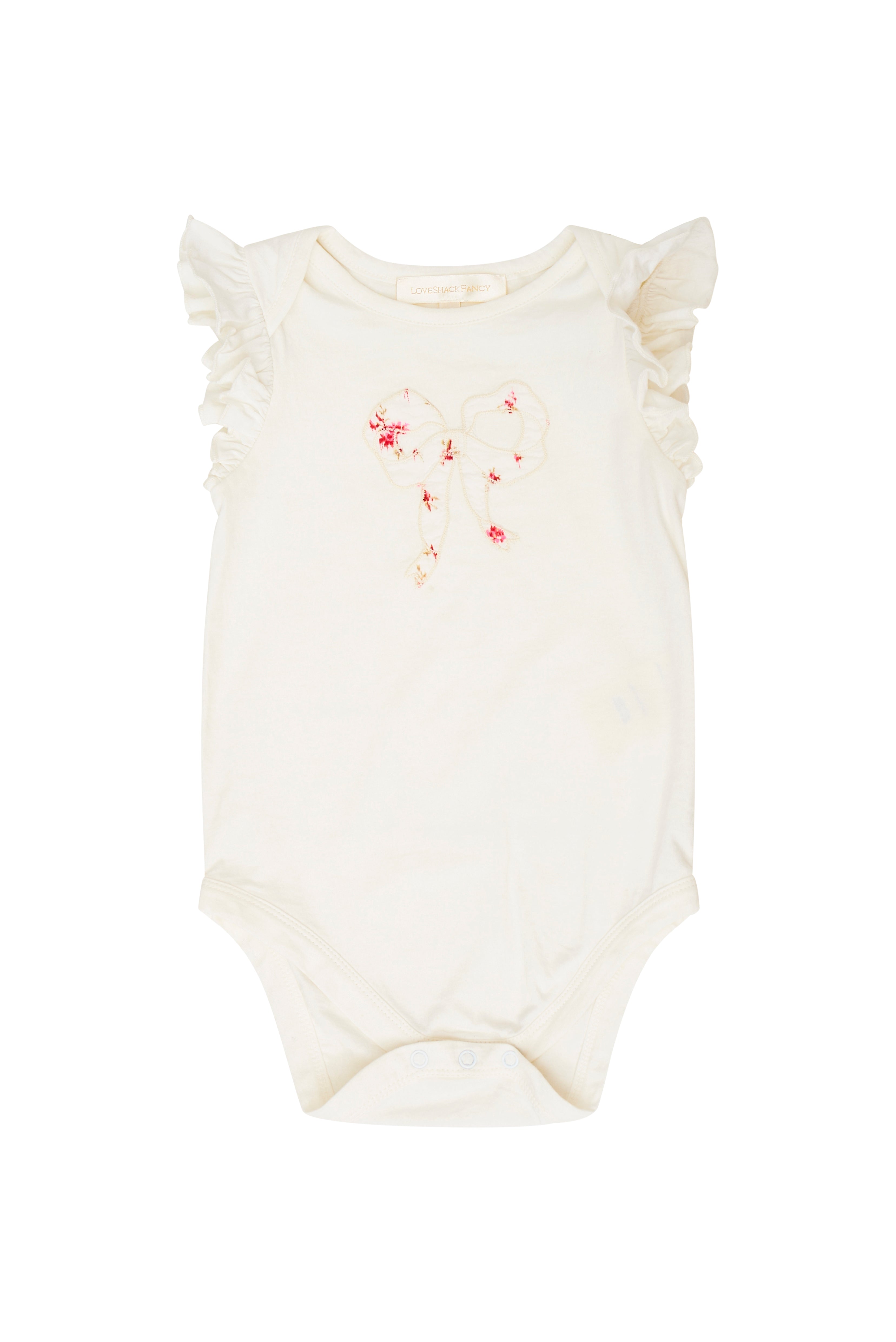 White onesie with ruffle shoulders and a floral embroidered bow stitched at front chest. 