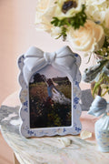 Decorative photo frame with a floral design on a table with flowers in the background