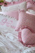 Pink and white bedding set with decorative pillows and heart-shaped pillow