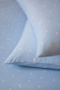 Blue sheets and pillow close up with white floral patterns, resembling a polka dot pattern.