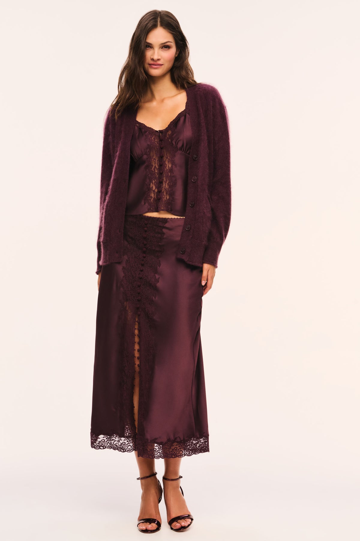 Deep plum satin cami with lace straps, lace v-neckline and lace front details, and button front closures, front view, styled with a matching skirt and fuzzy cardigan