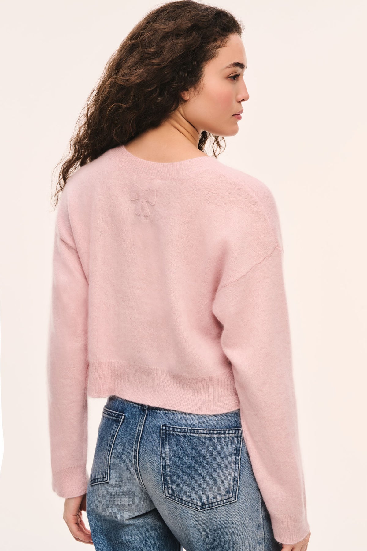 Pink crewneck knit pullover with long sleeves, back three-quarter view