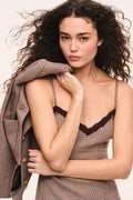 Close-up view brown and tan check mini dress with spaghetti straps and brown lace trim at neckline, on a model with a matching jacket over her shoulder