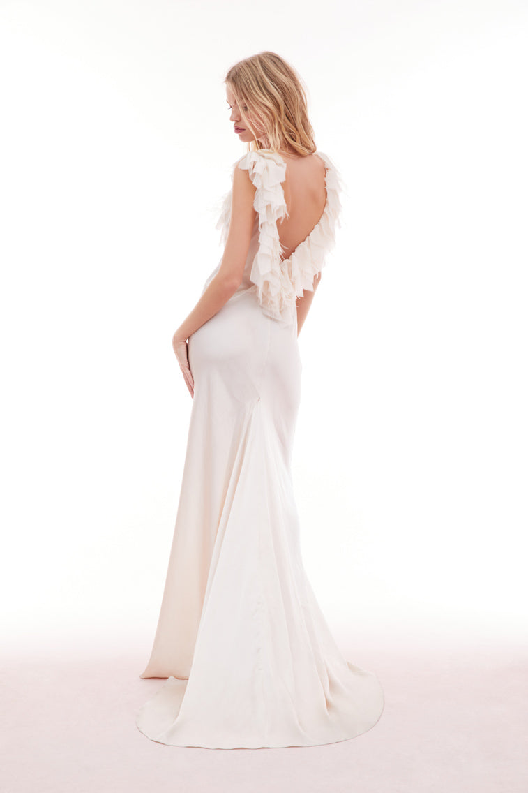 White gown with a deep v-neckline and form-fitting skirt with a train. Features an open back adorned with chiffon tatters and ruffles mixed in with accent feathers.