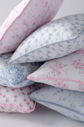 Stacked linen throw pillows, pink and blue floral prints, visible piping and seams
