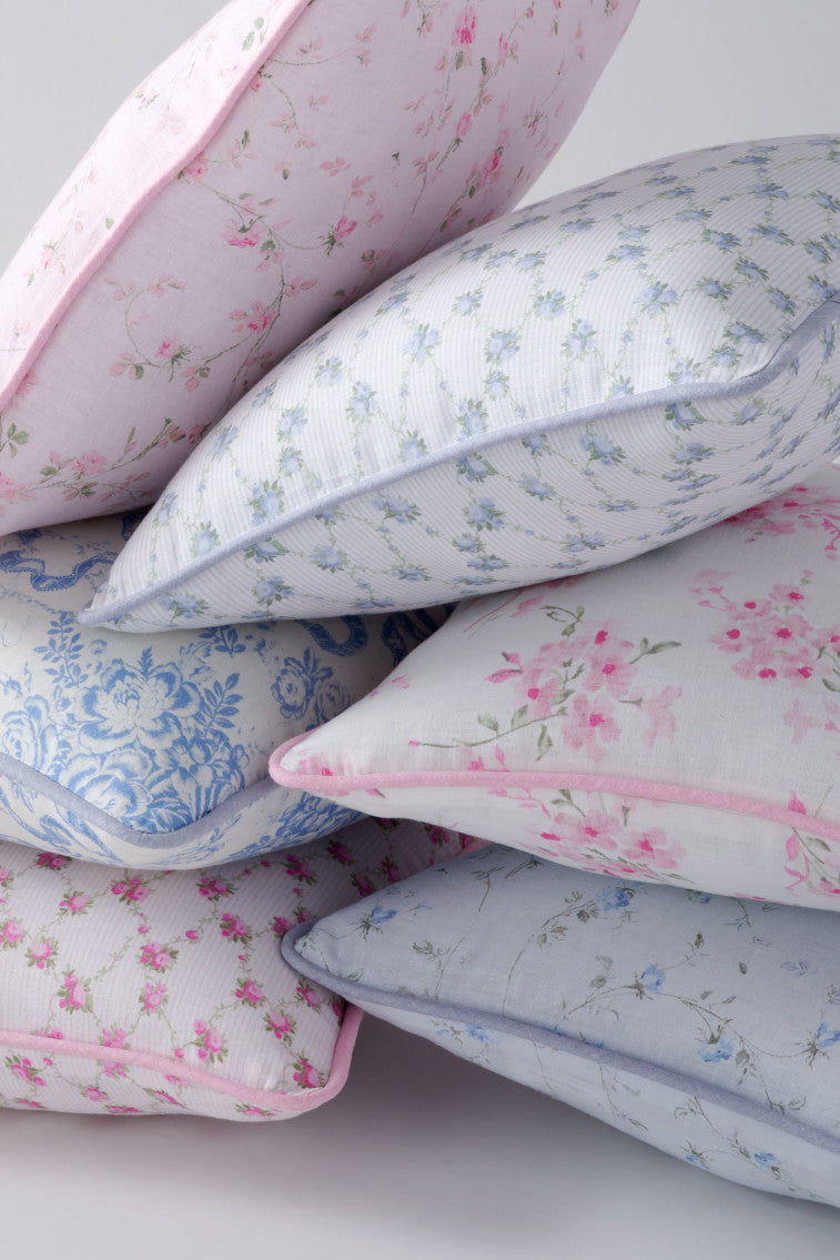 Stacked linen throw pillows, pink and blue floral prints, visible piping and seams