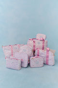 Floral print pink luggage collection against blue background