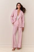 Woman wearing a pink suit against a plain background
