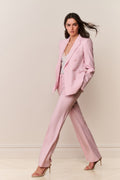 Woman wearing a pink suit against a plain background