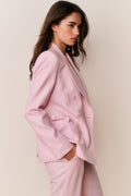Woman wearing a pink suit against a plain background