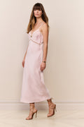 woman wears pink silk gown with lace detailing against beige background