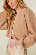 cashmere-wool blend cropped sweater, has a v-neck that descends to three buttons at center front. Pleated blouson sleeves extend to ribbed cuffs at opening.