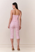 Woman wearing a pink gingham corset top and matching capris against a white background