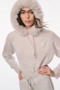 Woman wearing a light gray hooded outfit with fur trim on a white background