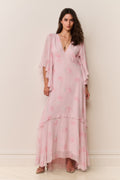 Woman wearing a pink dress with floral patterns against a white background