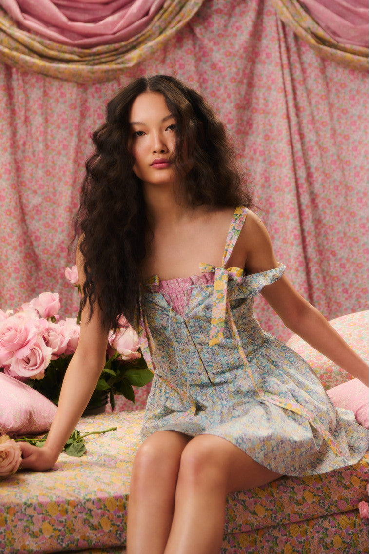 Floral printed mini dress with tank top straps and a tie detail at center front stint above a corset-inspired bodice that falls to a sweepy skirt.