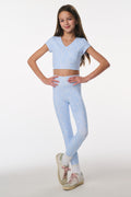 Girl wearing a light blue athletic outfit on a white background