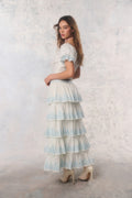 Woman wearing a layered dress with blue and white pattern against a light background
