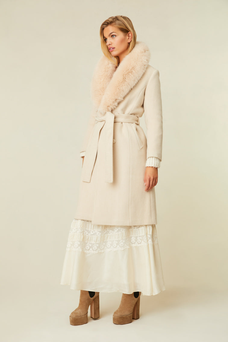 The cream-colored jacket features a faux fur collar, pockets, and a belt.