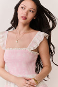 Woman wearing pink dress with lace details on a plain background