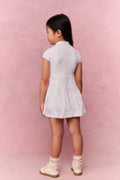 Young girl wearing a white t-shirt dress against a pink background