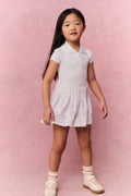 Young girl wearing a white t-shirt dress against a pink background