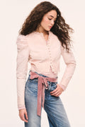 Light pink cropped jacket front view with button placket, puff sleeves, and lace-trim ruffle edges styled over a pink sweater