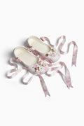 Pair of rubber shoes with pink ribbons on a white background