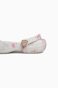White shoe with pink floral pattern and gold heart charm on a white background