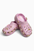 Pink croc clogs with decorative elements on a white background