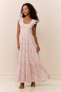 Woman wearing a maxi floral dress against a plain background