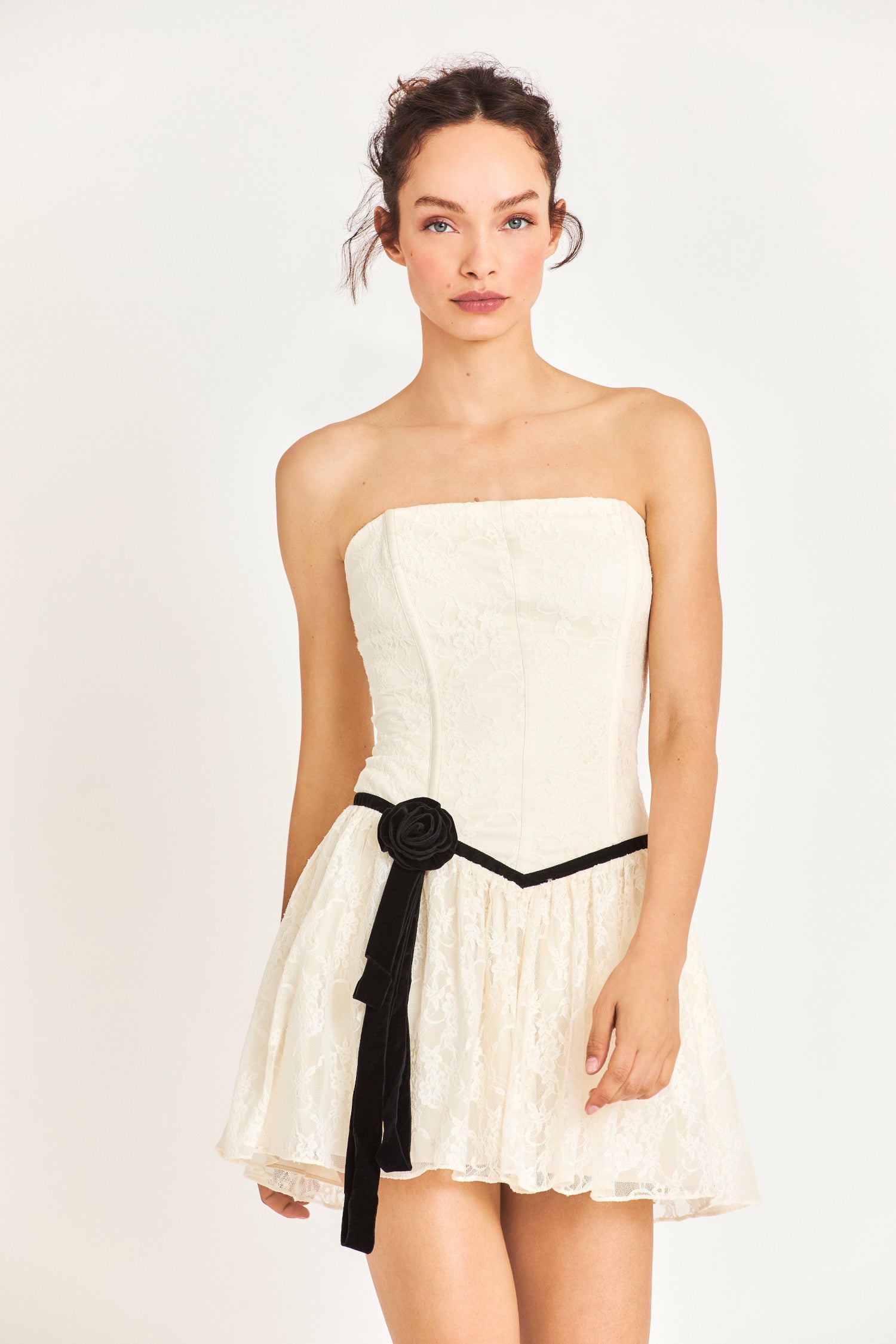Model wearing white strapless mini dress with black flower detail
