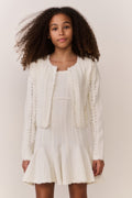 Tween wearing a white knit sweater and matching dress on a plain background