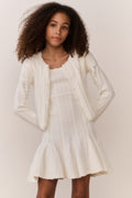 Tween wearing a white knit sweater and matching dress on a plain background