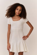 Tween wearing a white dress with a plain background