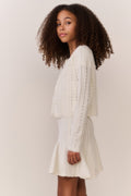 Tween wearing a white knit sweater and matching dress on a plain background