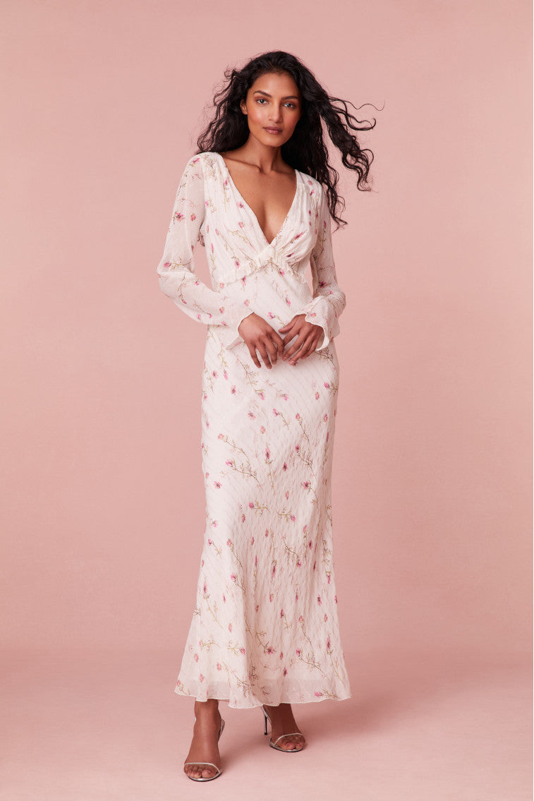 Floral maxi dress with fitted long bell sleeves, a ruched bodice, and stripes running throughout with ruffles on the waist. 