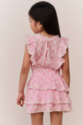 Young girl wearing a pink and white patterned dress against a plain background