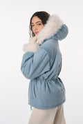 Woman wearing a blue winter coat with a fur-lined hood on a white background