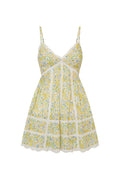 White mini dress with a yellow floral pattern with lace insets and pintucking details, and features a smocked back, spaghetti straps, and an airy skirt finished with lace.