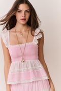 Woman wearing a pink ruffle top with lace details and matching skirt on a plain background