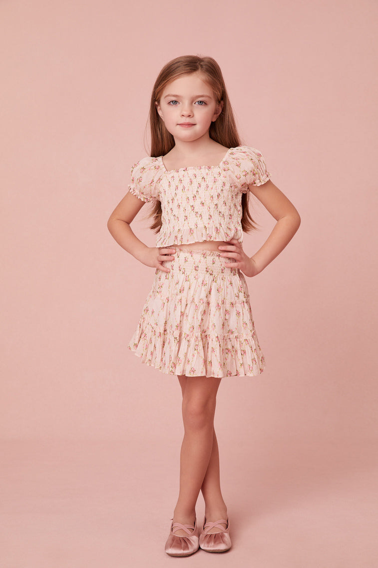 top features a dainty floral print, a smocked center front, short puff sleeves, and sweet ruffle detailing at the sleeve openings, neckline and the hem.