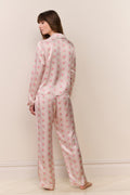 Woman wearing a pink floral pajama set against a white background