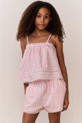 Young girl wearing a matching pink checkered sleeveless and shorts outfit against a plain background