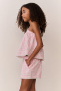 Tween wearing a pink checkered outfit against a plain background