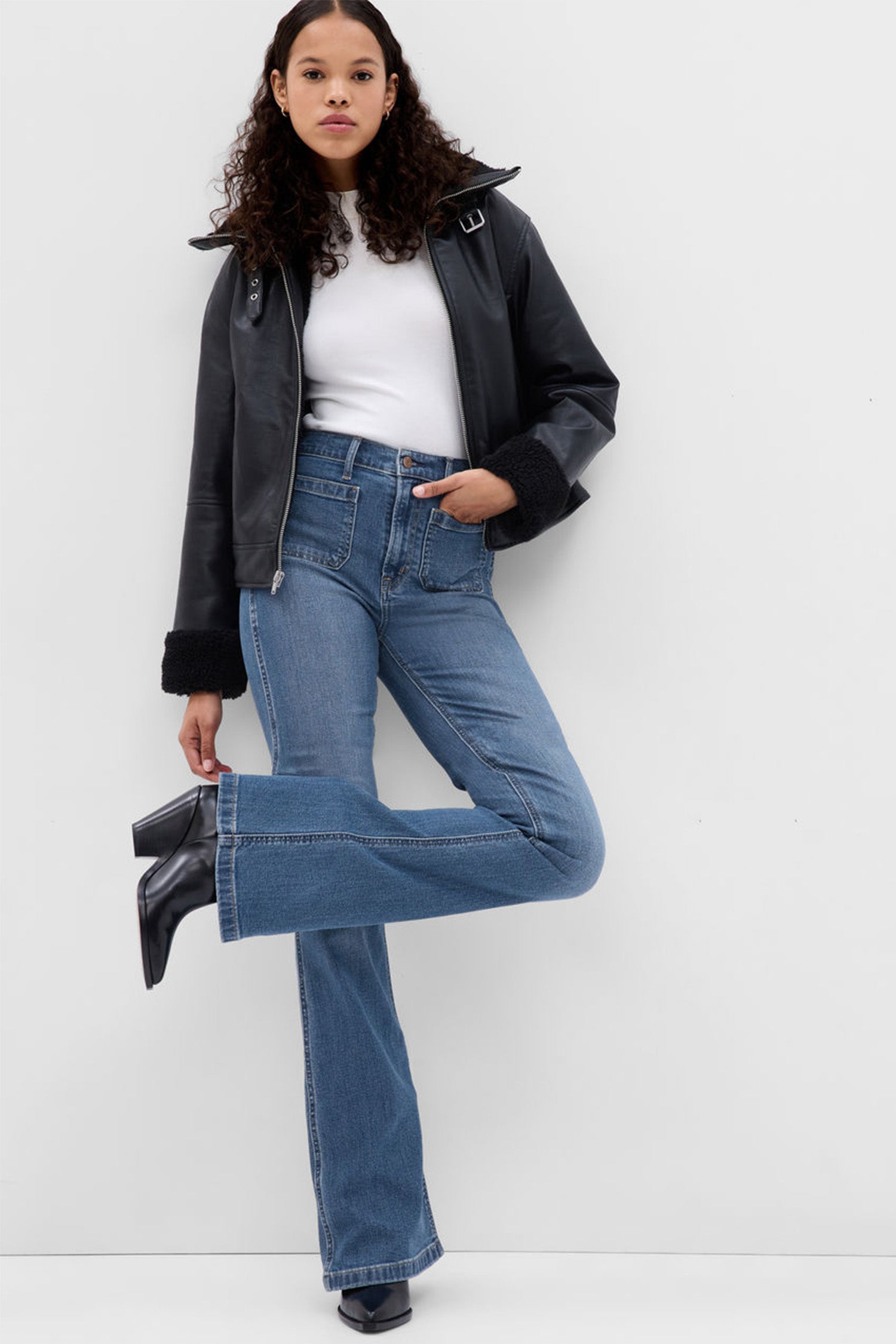 Model wearing blue high rise flare jeans with front pockets