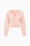 Pink cardigan with bow patterns on a white background