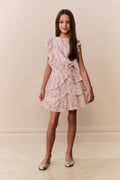 Girl wearing a floral ruffle dress against a plain background