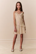 Woman wearing a light yellow dress with floral patterns against a beige background