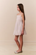 Young girl wearing a white dress against a beige background